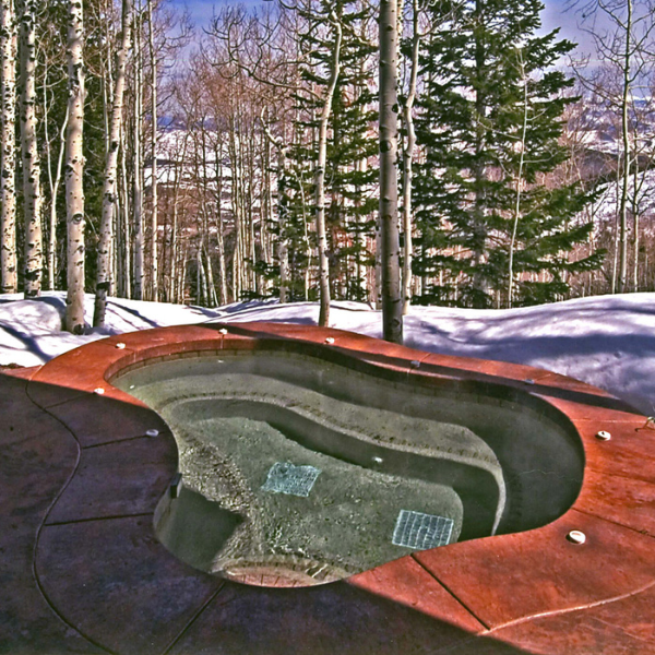 Experience ultimate relaxation in custom hot tubs or inground spas in Sandy UT, surrounded by snowy trees and a stunning forest backdrop with mountains on the horizon.
