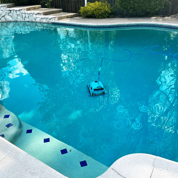 Robotic pool cleaner scrubbing a commercial pool floor and tile line