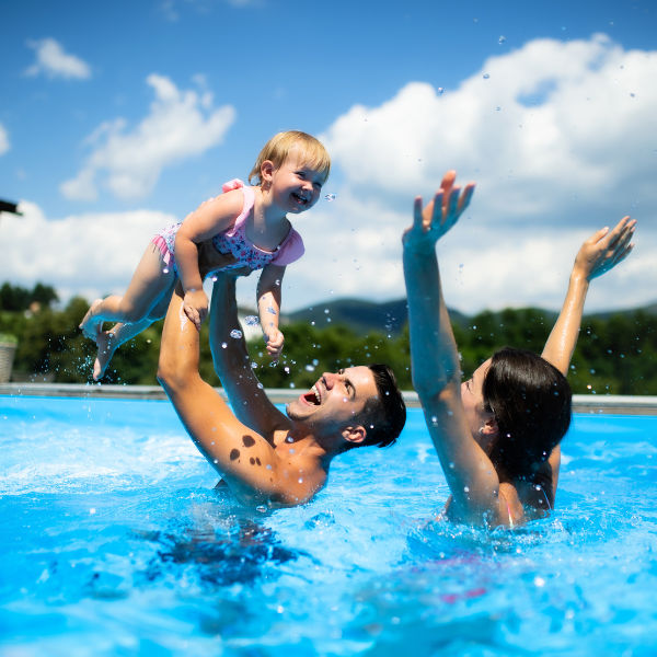 Happy family enjoying warm water in backyard pool.