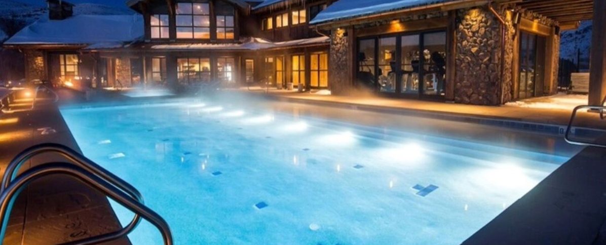 Backyard inground swimming pool with warm lighting and heater in use